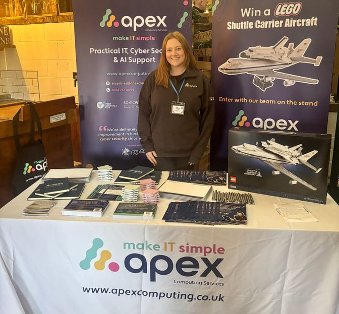 The image shows a person standing by a promotional booth for a company named 'apex' that offers practical IT, cybersecurity, and AI support.