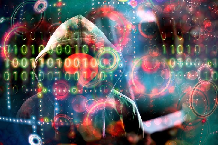 man in a hoodie with his face hidden covered by an overlay of cyber threat icons and binary code