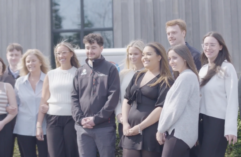 JLEs team standing outside a wooden building